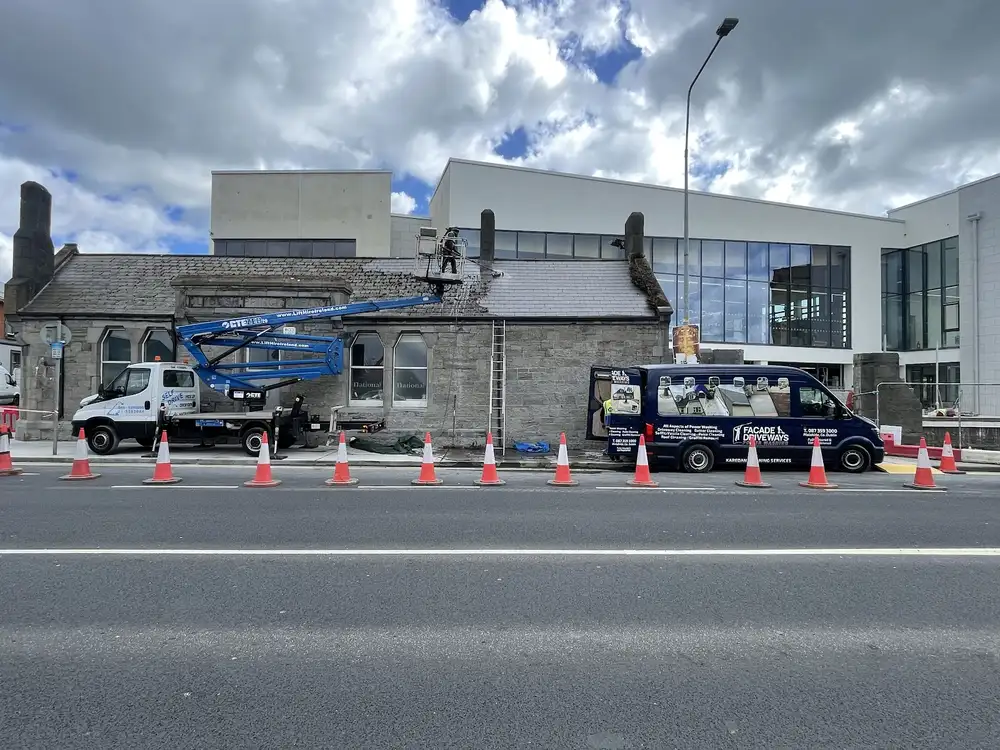 KAREDAN cherry picker and van cleaning the outside of a commercial building, with the road coned off